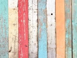 Texture of vintage wood boards with cracked paint of white, red, orange, yellow, cyan and blue color. Retro background with old wooden planks of different colors