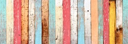 Texture of vintage wood boards with cracked paint of white, red, orange, yellow, cyan and blue color. Horizontal retro background with old wooden planks of different colors