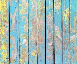 Texture of vintage wood boards with cracked paint of yellow, cyan and blue color. Horizontal retro background with old wooden planks of different colors