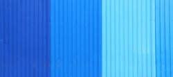 Wave Sheets fence of dark blue, blue and cyan colors. Horizontal background with galvanized iron sheets of different shades of blue color. Colored corrugated metal roofing sheet