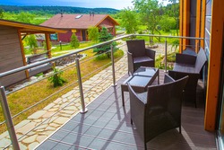 Country holiday. Terrace of a country house. Concept - abeautiful view opens from terrace. Armchairs and a table are on balcony. Concept - rental of a country house. Houses among northern nature.