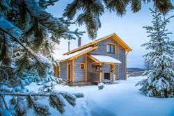 Winter landscape. Cottage on the background of snow-covered fir branches. Wooden house in the countryside. Christmas and New year in cottages. Rent a country house for a large company.