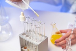 Researcher is testing vaccine. Synthesis of vaccines. The doctor adds a yellow substance in test tubes. The scientist mixes the elements of the vaccine in glass tubes. Drug development, pharmacology.
