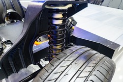 Car suspension spring. New spring over wheel of car. Concept - repair of suspension system. Replacement of spare parts in car. Replacing vehicle suspension. Cushioning system in auto.