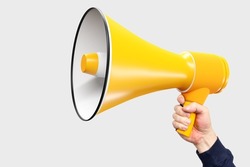 Hand with yellow loudspeaker. Man holds out loudspeaker. Place for text next to megaphone. Copy space on white background. Loud-hailer symbolizes ads and promotional calls. Agitation metaphor