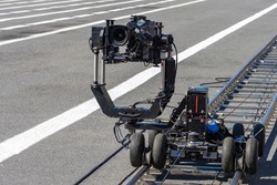 Video camera on rail carts. Specialized operator equipment. Professional video filming Concept. Rails on pavement for filming equipment. Camcorder shoots outdoors. Automatic video camera