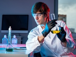 Male chemist with a flask in his hand. Scientific research in the chemical laboratory. Discoveries in the field of chemistry. Chemist working in a laboratory and doing research. Passion for chemistry.