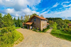 Vacation home. Two-story wooden house. Country cottage view from copter. Stone paved path in front of cottage. Country hotel in summer weather. Suburban house and blue sky. Scandinavian style house