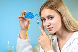 Woman demonstrates brain model. Young neuroscientist girl. Female neuroscientist points her finger at brain. Brain and socket symbolize intellect. Learning ways of self-development concept