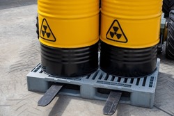 Barrels with toxic products. Barrels with symbol of radiation hazard. Plastic pallet with radioactive liquid. Concept toxic industry. Toxic waste in yellow barrels. Transportation radioactive liquid