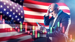American investor. Man with tablet grabs his head. Businessman near American flag. Businessman from USA went bankrupt. Losses in US financial market. Bankruptcy company in United States of America