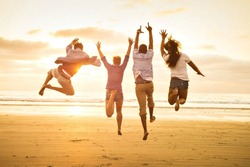 group of happy young people dancing on the beach