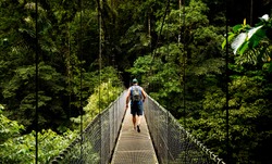 Man walking on a hanging bridge in Arenal Volcano National Park - Costa Rica
