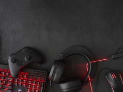 gamer workspace concept, top view a gaming gear, mouse, keyboard, joystick, headset, mobile joystick, in ear headphone and mouse pad on black table background with copy space.