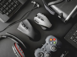 gamer workspace concept, top view a gaming gear, mouse, keyboard, joystick, headset, webcam, VR Headset on black table background.
