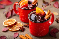 Two cups of autumn mulled wine or gluhwein with spices and orange slices on rustic table top view. Traditional drink on autumn holiday on the background of autumn leaves