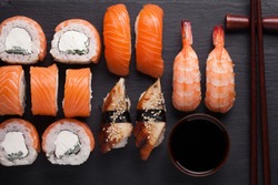 Close-up sushi Set sashimi with salmon, shrimp, eel and sushi rolls philadelphia served on stone slate. Top view.