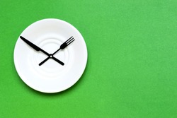Time to eat and diet concept, plate as a clock on the green background. Place for text.