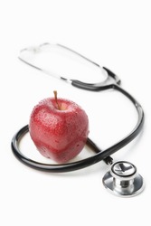 Stethoscope and a red apple over white for health lifestyle concept