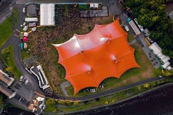 Concert of beer festival area with big red tent and service areas. Big crowd enjoy all amenities. Aerial top down view. Music event or circus in town. Entertainment industry and business.