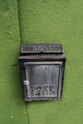 Old metal mailbox on a green wall. Retry style.