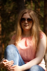 Portrait blondie girl wearing sunglasses sitting on green grass