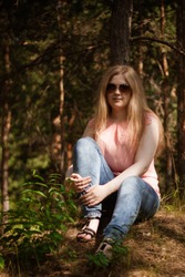 Portrait blondie girl wearing sunglasses sitting on green grass