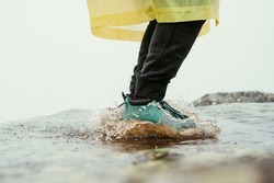Legs in boots man tourist jumps into a puddle in the mountains with splashes of water foto.Man jump into a puddle.