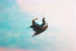 Lonely man on a dreamy, cloud-like background on a bed. Floating miniature figure in a dreamscape of blue and pink. 