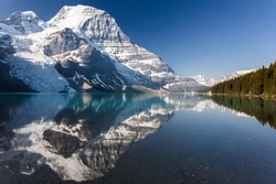 Panoramic view of Mt Robson mountain with glacier and lake during day with amazing summer colors in daylight and blue sky no clouds and mirror reflection in the water , Canadian Rockies in Canada.