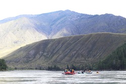A sporty and dynamic shot of sportsmen rafters on the Katun river. Altai Republic, Russia. Extreme sportsmen in the fast flow of a mountain river in a calm area.