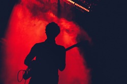 Guitarist silhouette in stage lights. Rock, punk concert. 