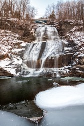 Multi tiered waterfall cascading down rocks in a snowy winter wonderland scene. She-Qua-Ga Falls - Montour Falls New York. 