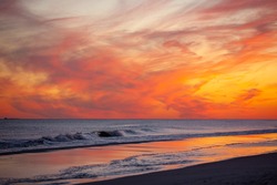Vibrant pink and orange sunset over small waves breaking on the beach. Jones Beach, Long Island New York