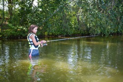 Young teenage girl fishing in the water with rod