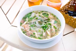 Pho noodle, traditional Vietnamese food, rice noodle soup with sherd chicken and topped with vegetables or herbs such as fresh cilantro, fresh mint and fresh Thai basil, then served with cups of tea.