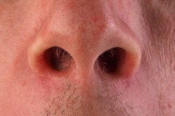 Front view of man's nose and upper lip with the mouth just visible. An image of a nose hair.