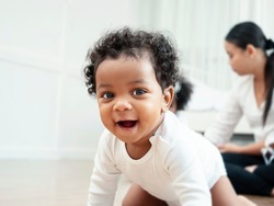 The American Afican boy is crawling and smiling for the camera.