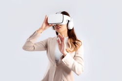 Asian businesswoman in beige color jacket suit wearing vr goggles hand touching on white screen background.