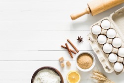 Baking ingredients on white table. White eggs, rolling pin, flour, sugar and spices. Home baking concept, baking cake or cookies ingredients