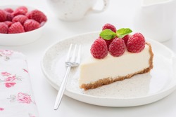 Cheesecake slice with raspberries on white plate. Slice of plain cheesecake. Raspberry cheesecake. Tasty cheesecake
