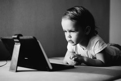 Little boy watching video on the tablet. Monochrome portrait.
