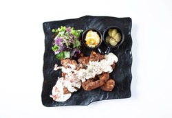 Hot bacon chicken with garnish in black square plate