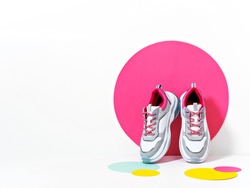 Bright lit scene with chunky sneakers and huge confetti. Colorful casual wear or footwear. Minimalist fashion fitness creative concept.