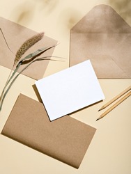 White empty card with stationery set of envelopes, notebook, pencils. Blank card styled mockup with hard light and shadow. To do list, greeting card or writing a letter concept.