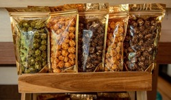 Many delicious popcorn varieties of flavors are in the packet bag on the wooden table.