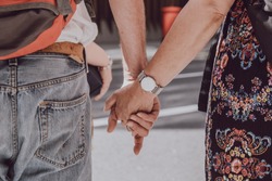 Close up of unidentified Caucasian couple holding hands in public, love concept, selective focus.