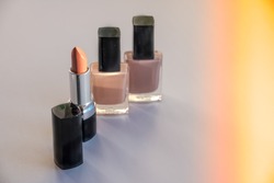 Various Cosmetics isolated on white background. Sun rays. Copy space.Decorative cosmetics.Fashion colors concept.Nude makeup.Selective focus.Nail polish,nail varnish bottles and beige lipstick.