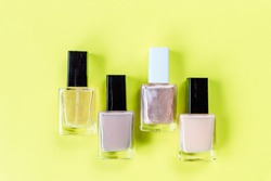 set for nail polish on yellow table background top view mock up.collection of various nail polish bottles.Nude collors. Nails care. Manicure, pedicure beauty salon