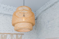 Pendant light with wicker lampshade, rustic style.Wicker shade lamp.Simple home interior with decorative ceiling wicker lamp.Decorating hanging lantern lamps in wooden from bamboo